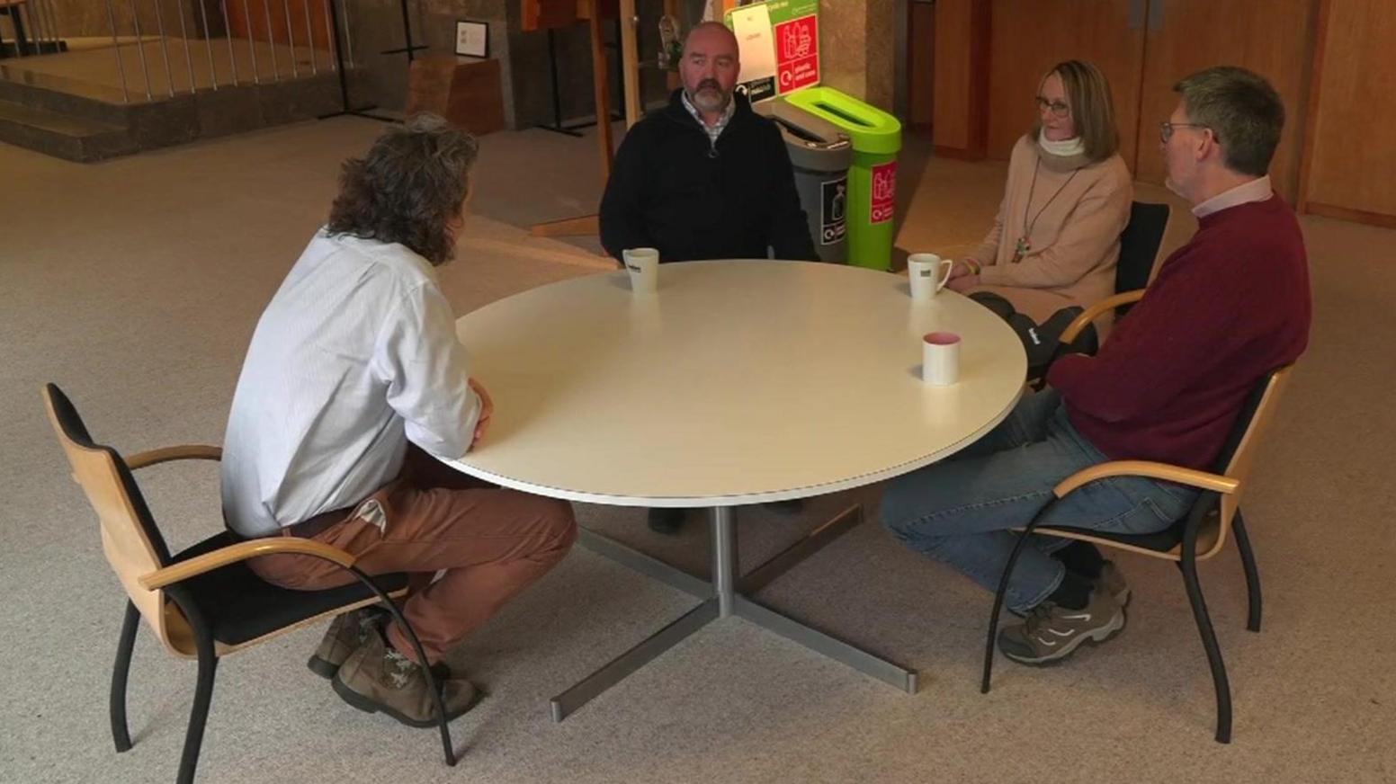 Three hosts sit around a table at County Hall in Truro talking to a BBC journalist 