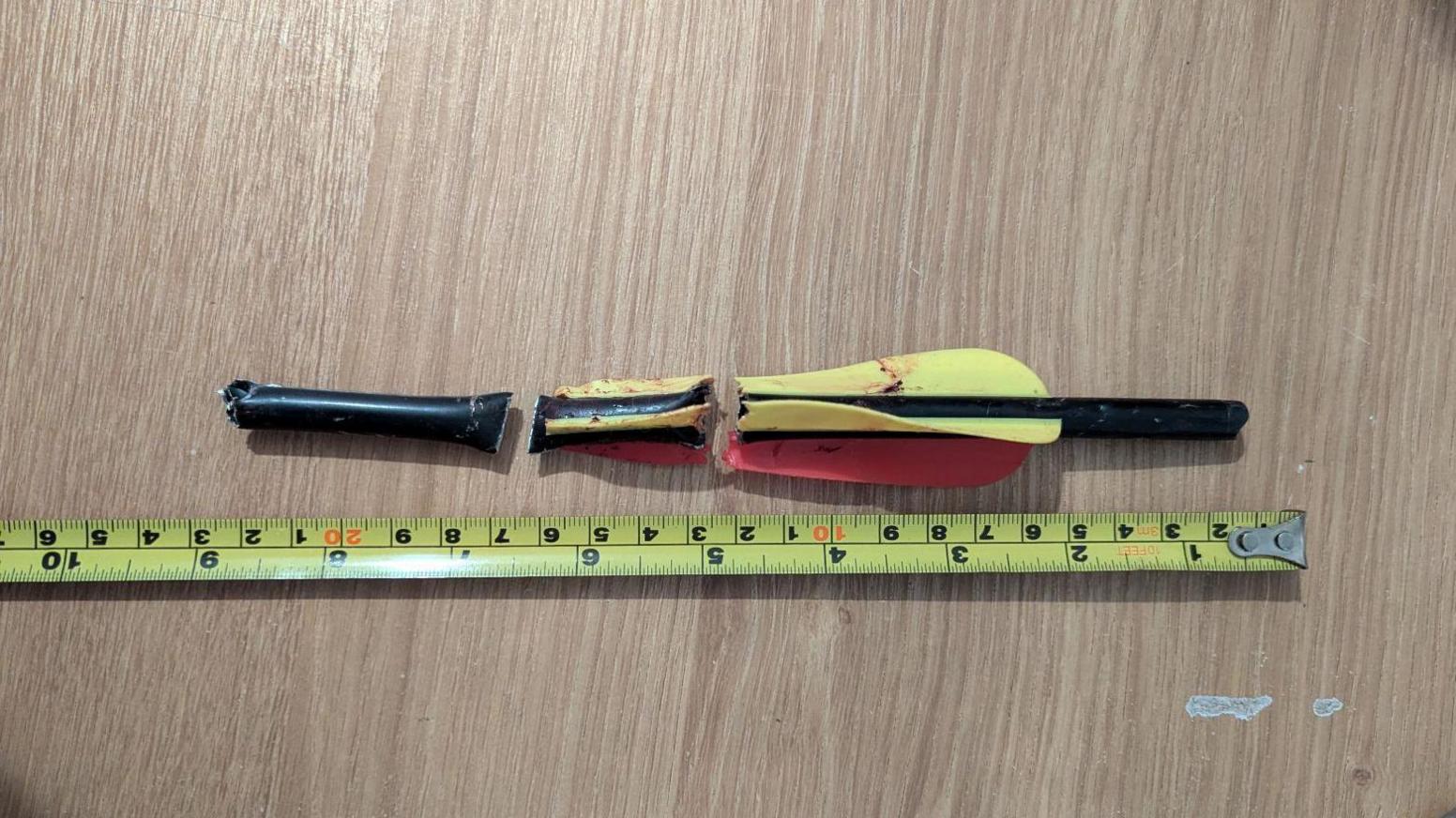 The red and yellow bolt, cut into three sections after being removed from the dog.  It has a measure next to it, that shows the bow was about 9 inches long.