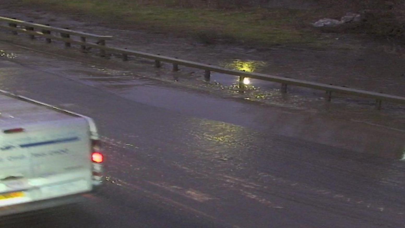 Still from Traffic Scotland webcam showing a dark section of road with dark water flooding on one side