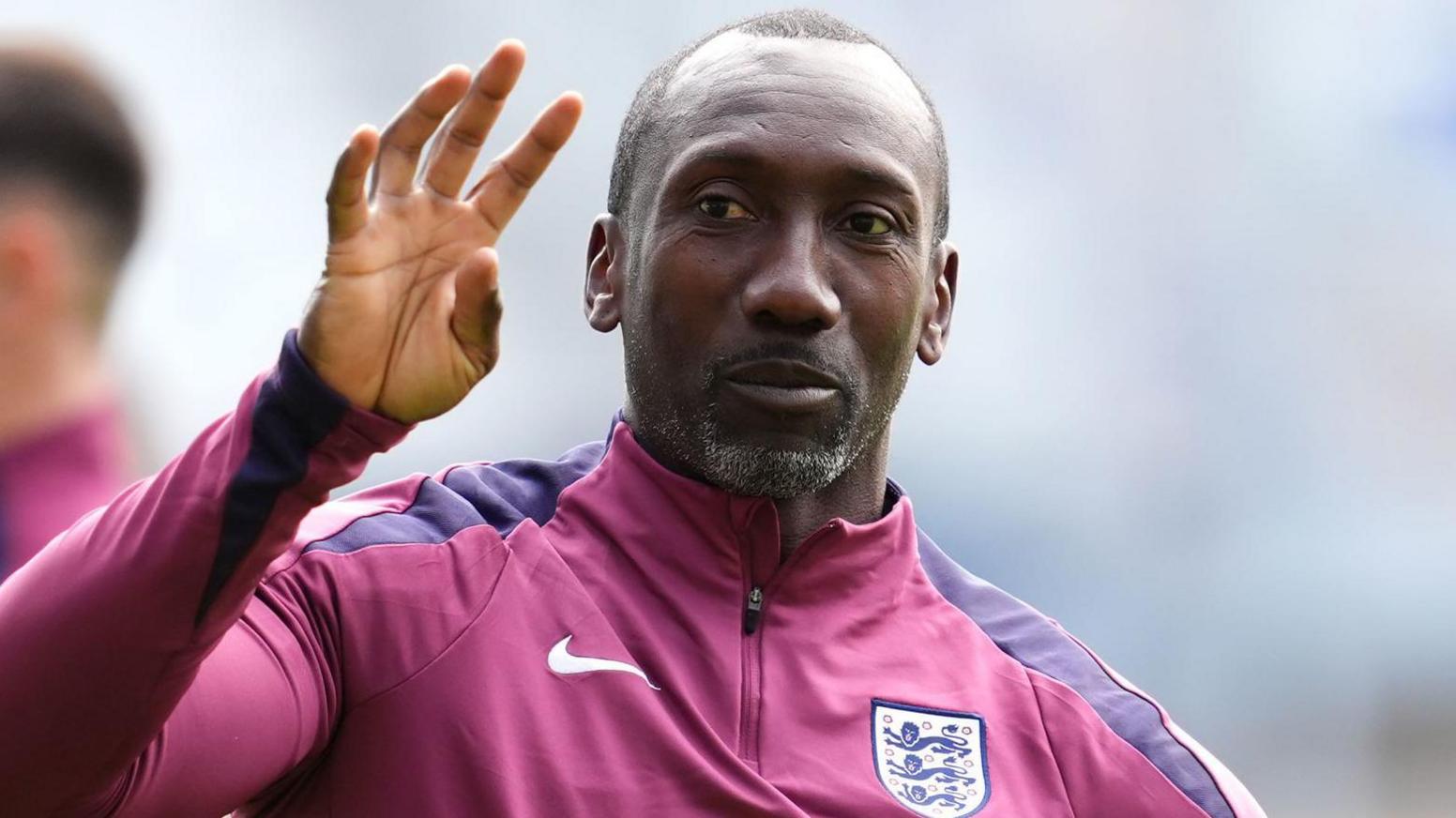 Jimmy Floyd Hasselbaink with an England training top and one hand raised