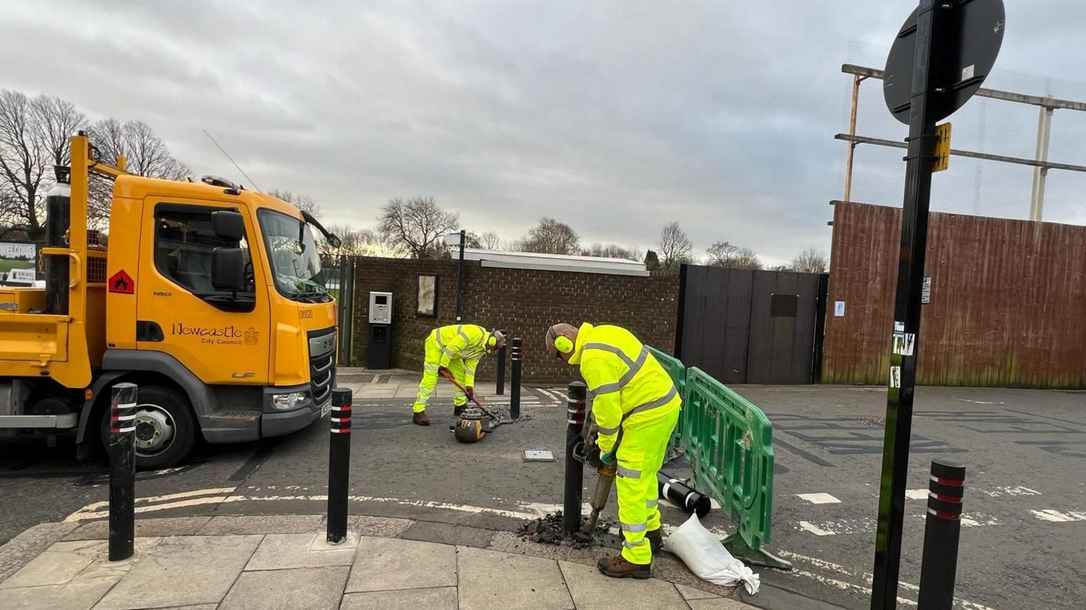 Workmen removing bollards