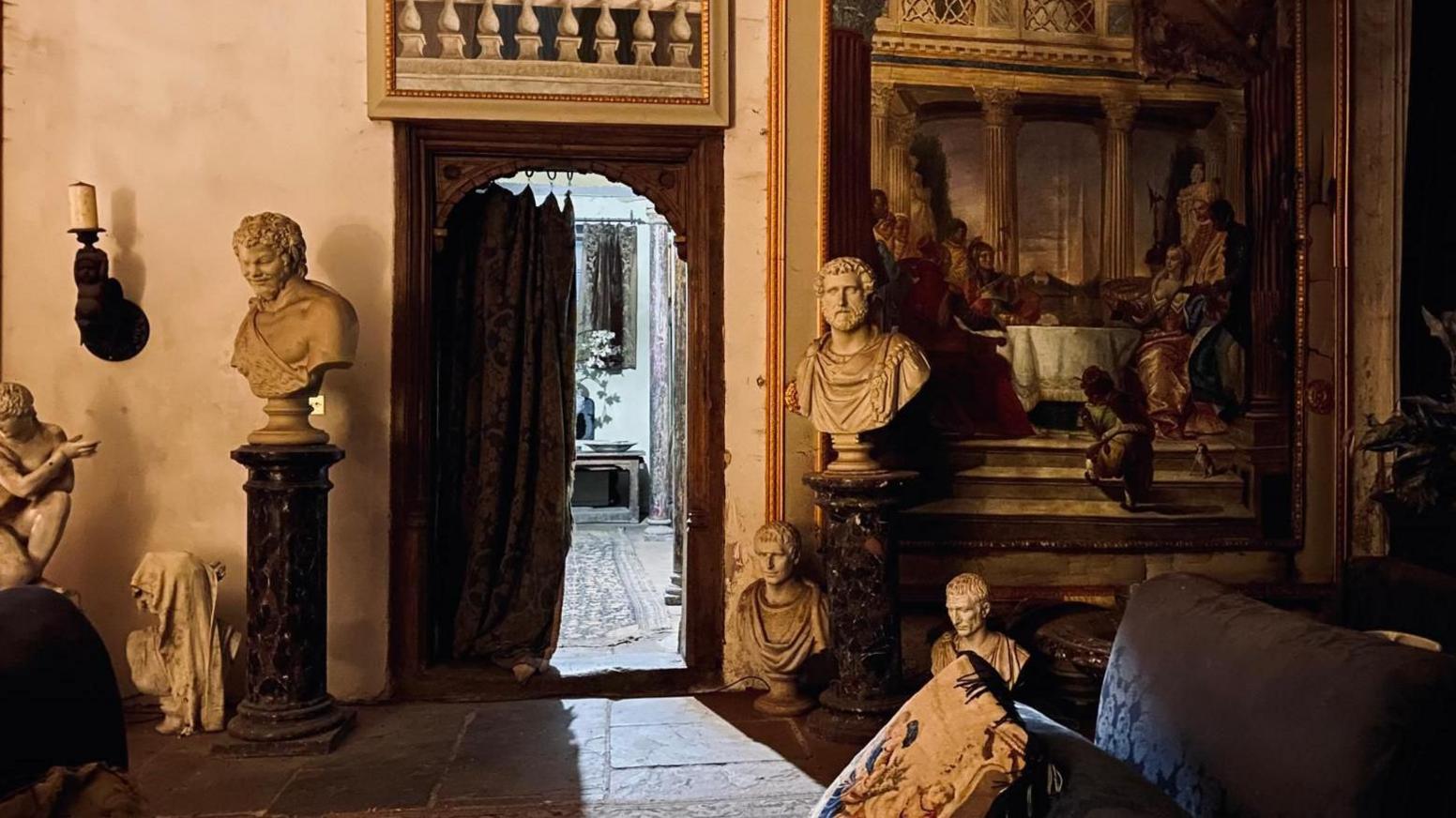 Several busts and sculptures situated on plinths and on the floor, in one of the rooms of Plas Teg