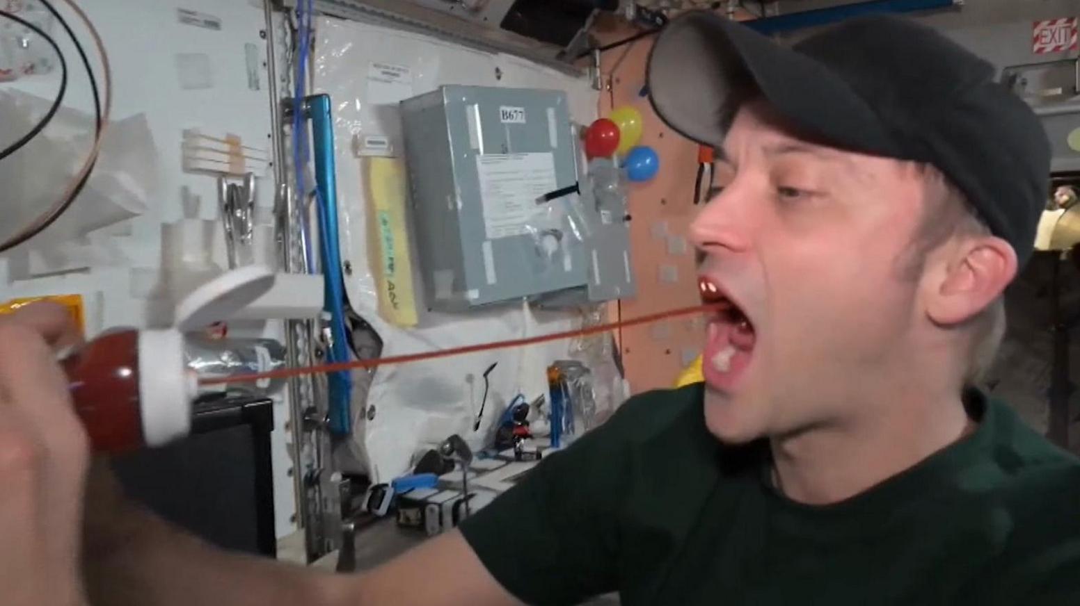 Astronaut Matthew Dominick squirting ketchup into his mouth on the International Space Station