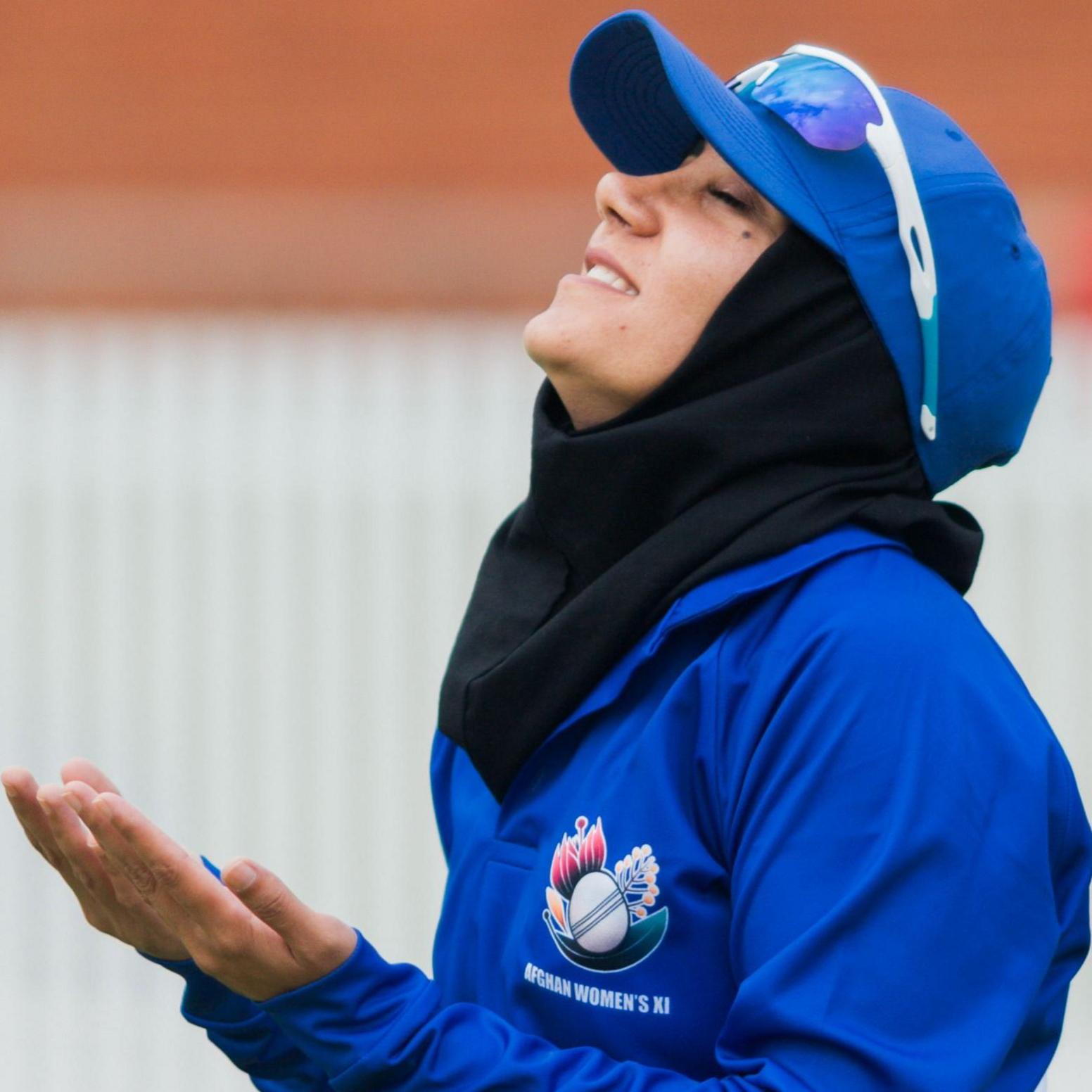 Afghan player Tooba Sarwari looks up with her hands held out during her team's match against Cricket Without Borders