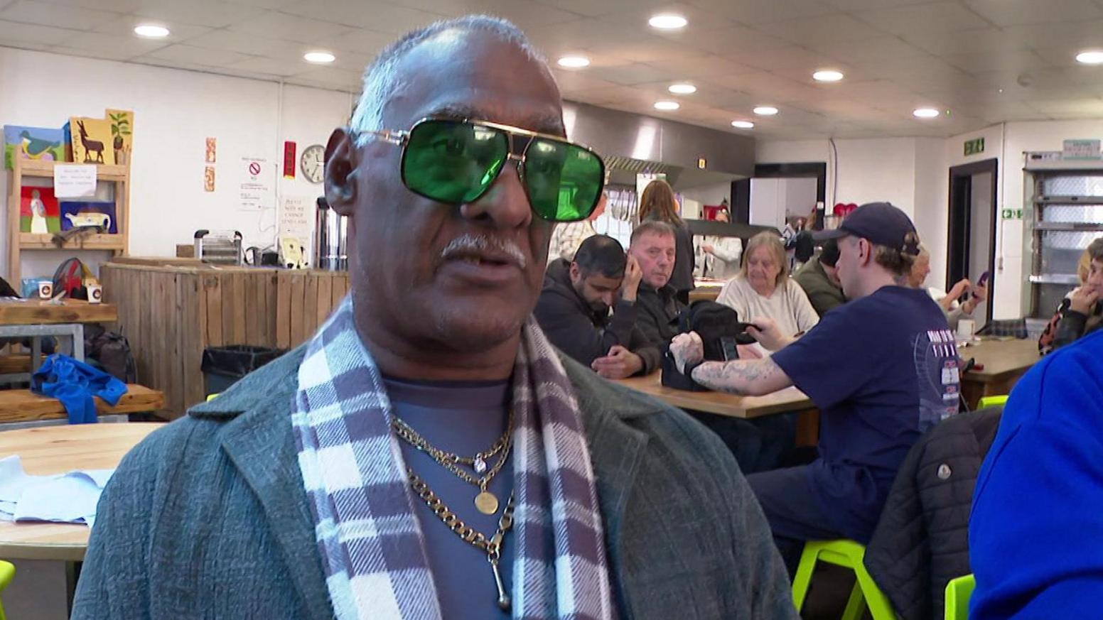 Man with grey hair wearing glasses sat at table