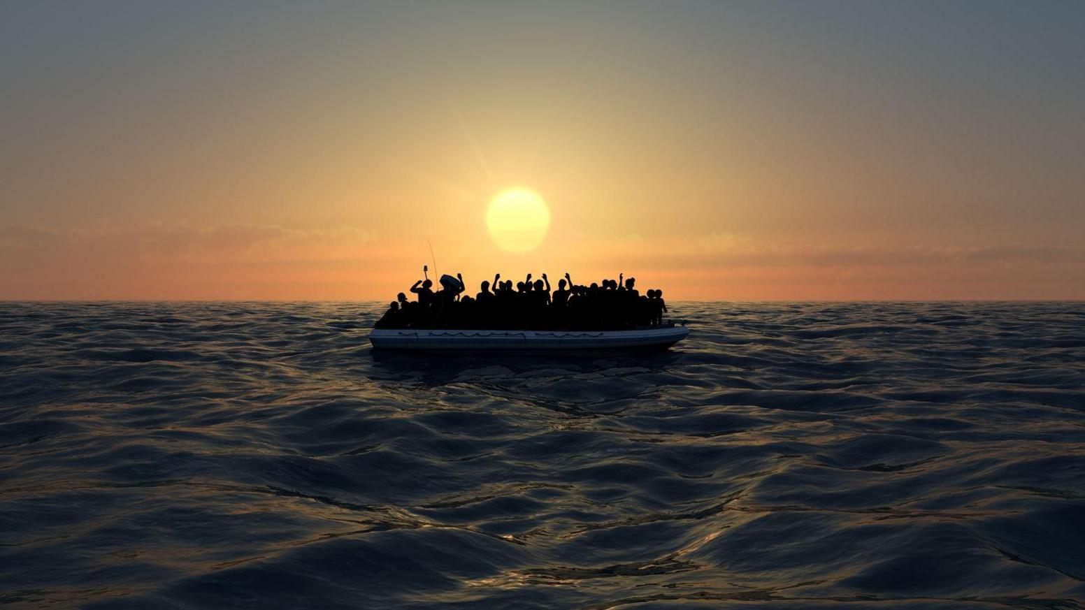 The silhouette of a crowded small boat on the sea with the sun setting in the background.