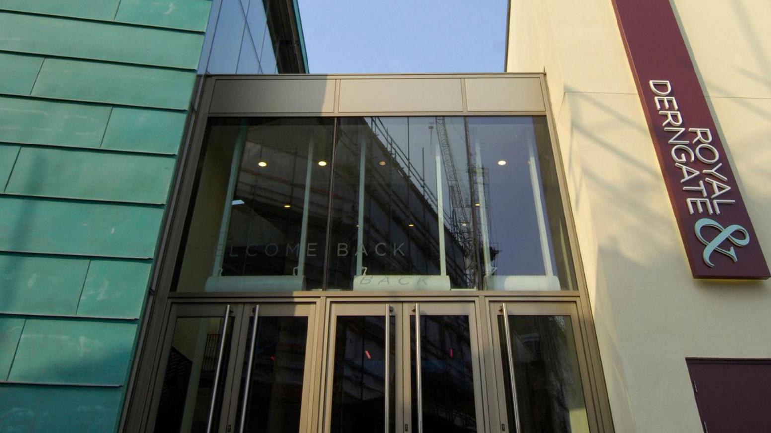 A glass frontage with a maroon Royal & Derngate vertical sign to the right of the doors. 