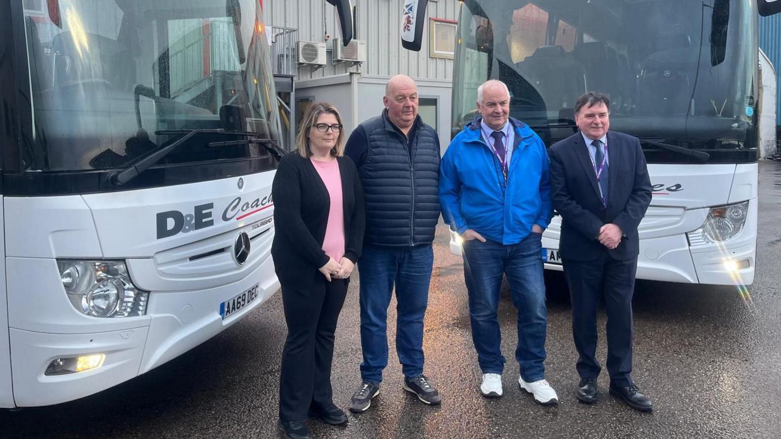 Key figures in the bus deal - Gayle McEwan, general manager D&E Coaches, former owner of D&E coaches Donald Matheson, Leader of Highland Council Raymond Bremner and chair of economy and infrastructure committee, Councillor Ken Gowans - stand in front of two white buses.