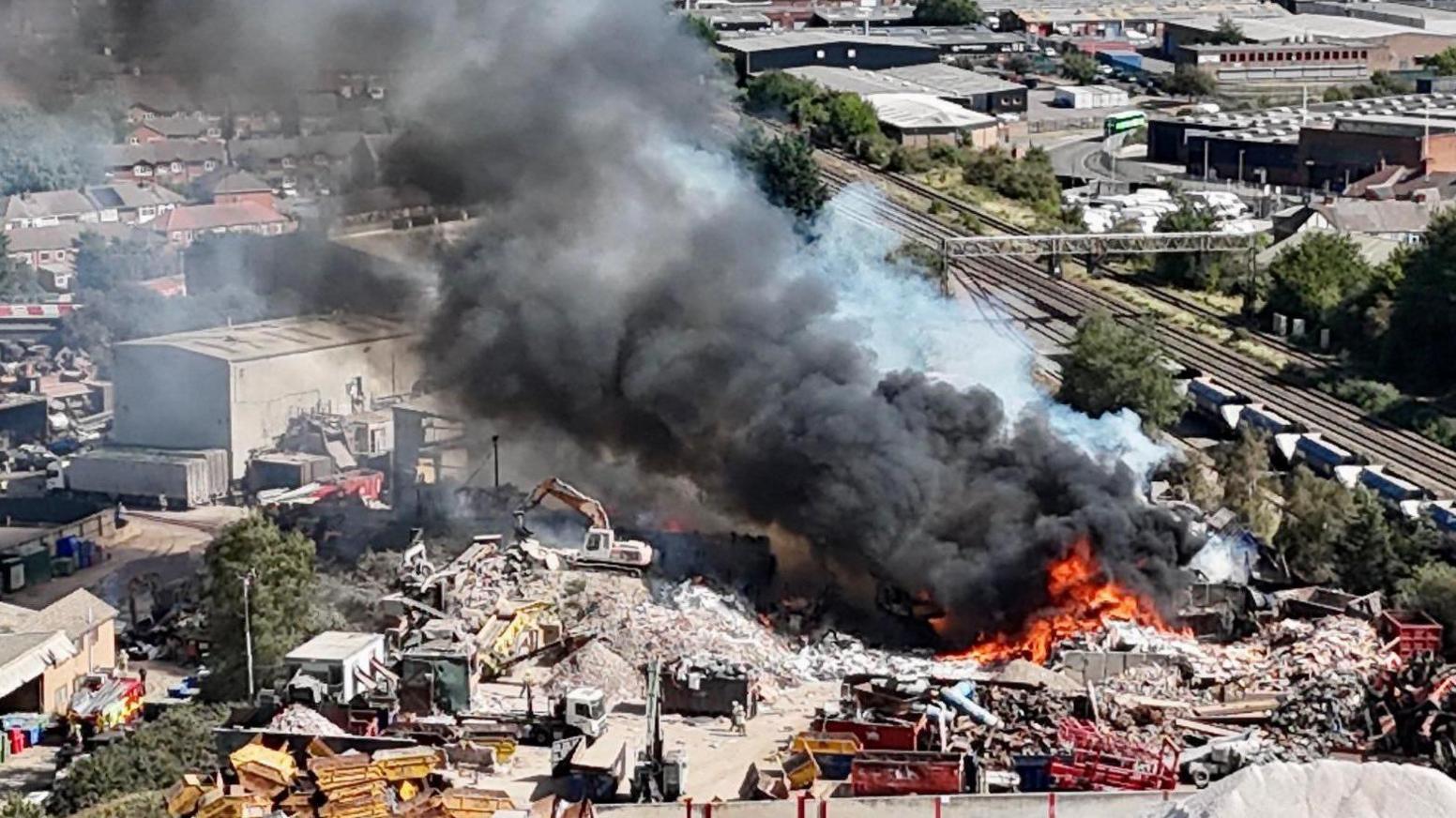 Drone shot of flames and smoke coming from an industrial yard.