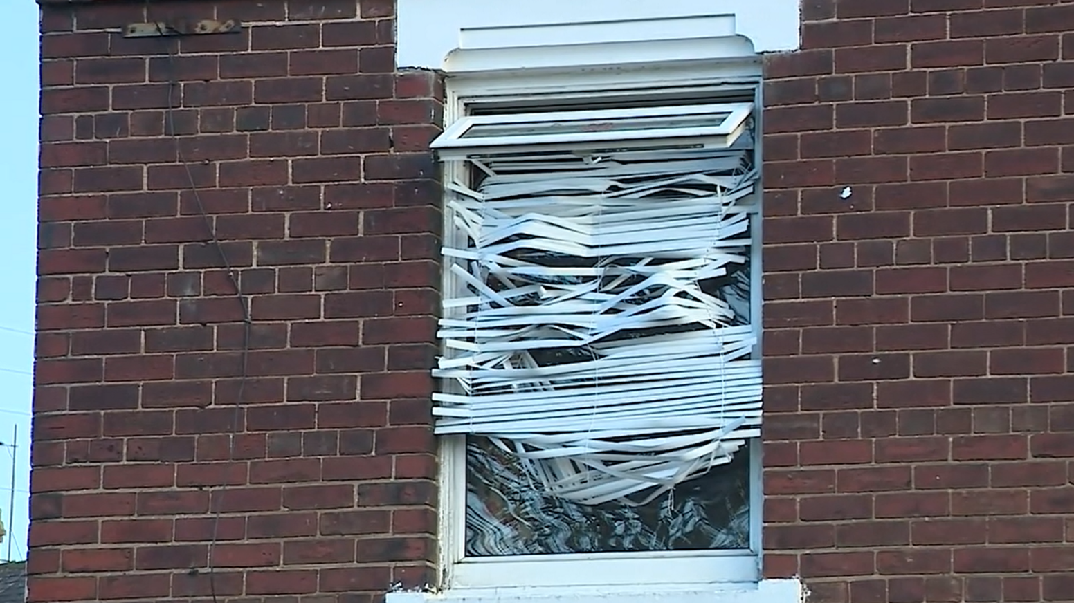 Upstairs window of the property with damaged blinds