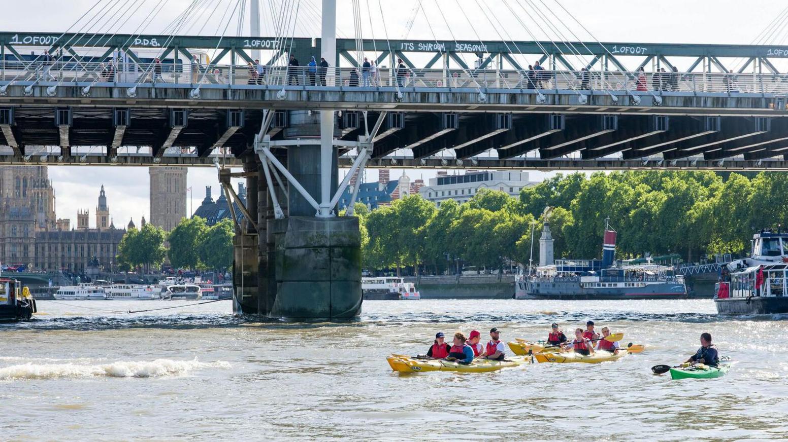 The challengers are kayaking under a bridge in London, the Houses of Parliament in the background.