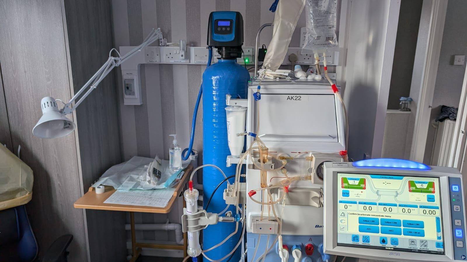 A blue and white dialysis machine with a screen and wires showing.