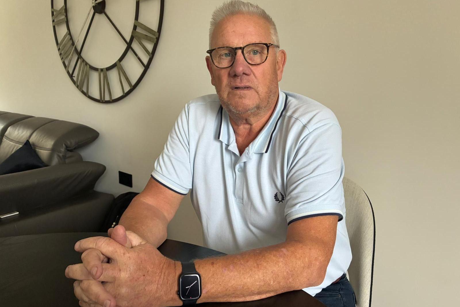 Image of David sat at his dining table. He has glasses and is wearing a light blue Fred Perry polo.