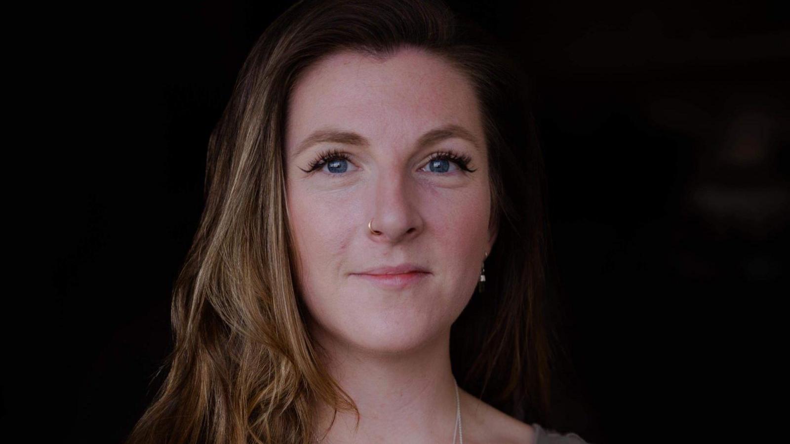 A portrait photo of Hannah with long brown hair smiling at the camera.