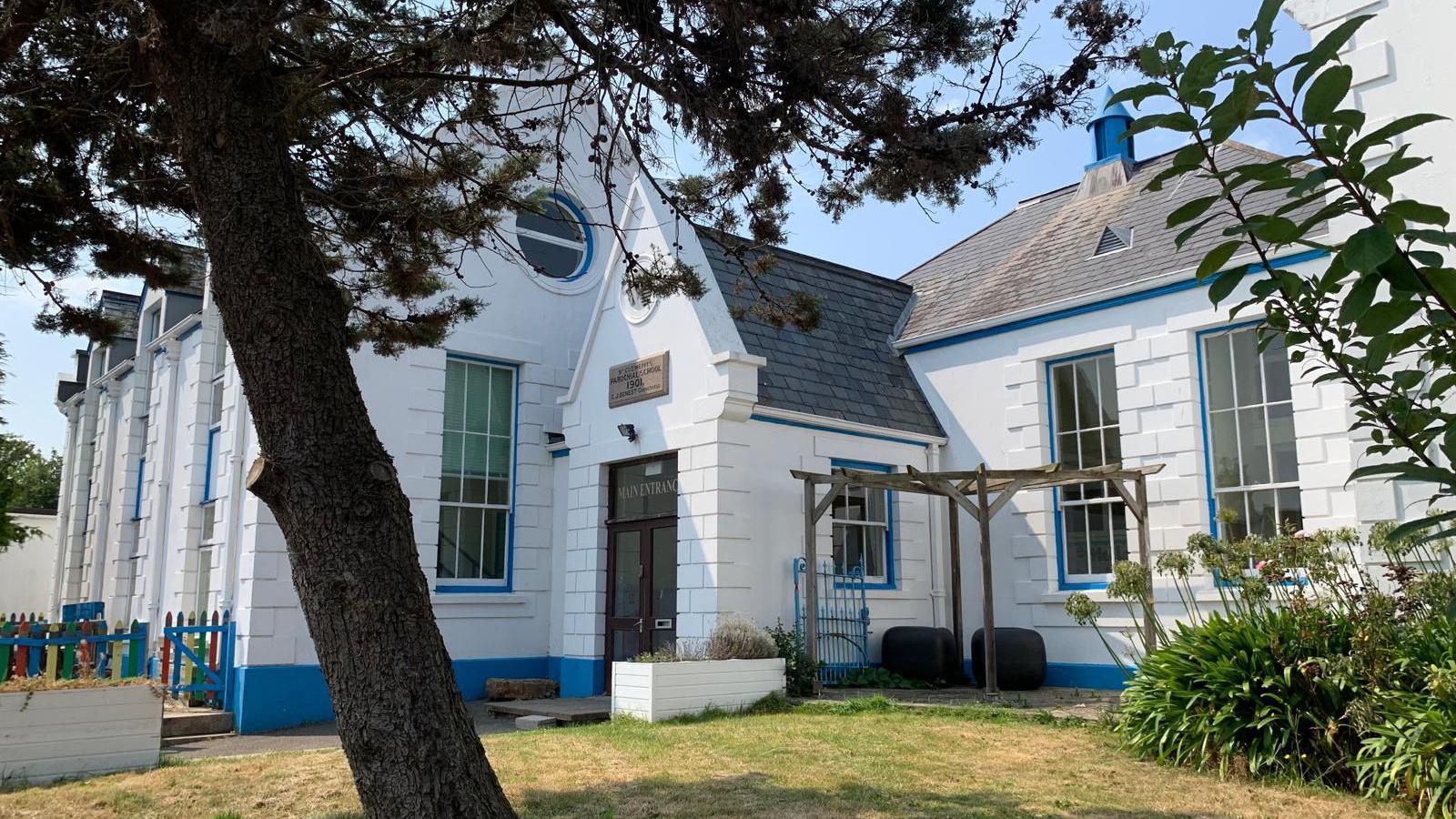 St Christopher's School is a white building with blue trim. It has grass and a tree in front of it.