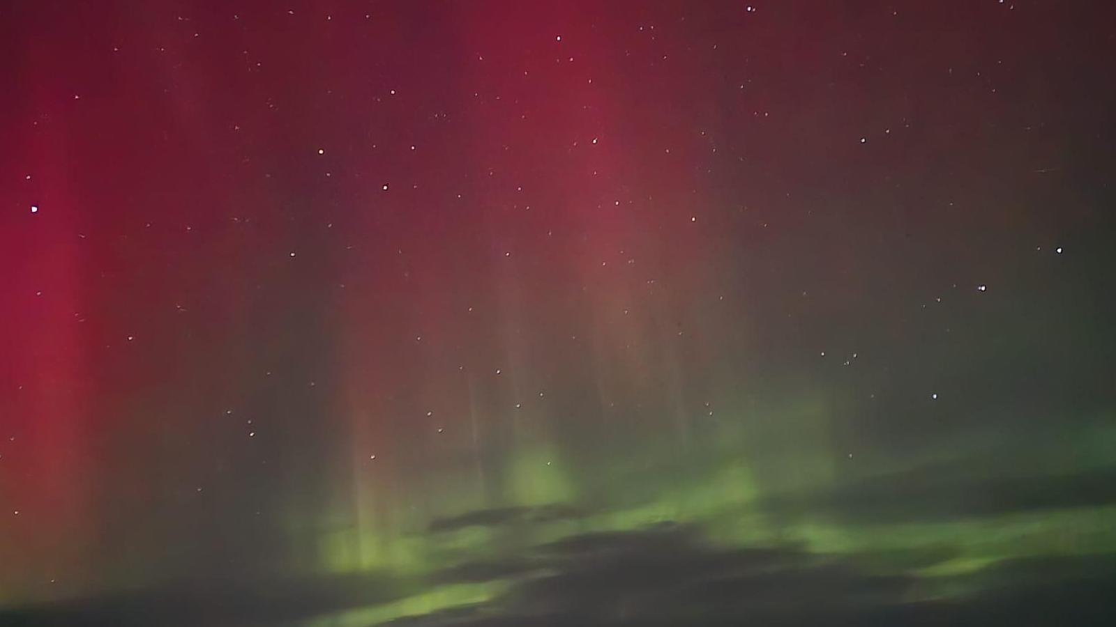 Red and green aurora in a starry night sky