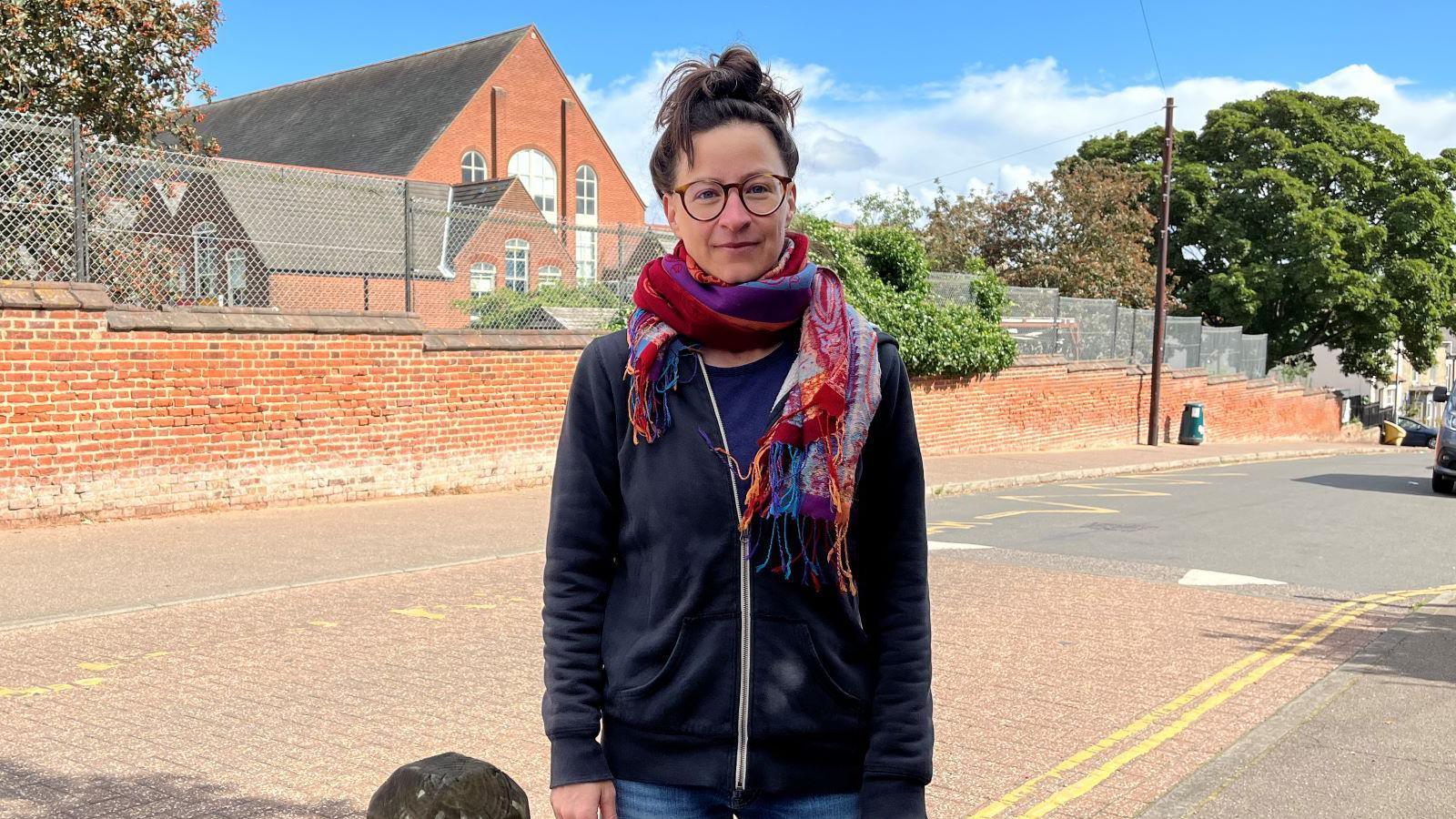 Woman wearing black jacket and brightly coloured scarf outside a school.