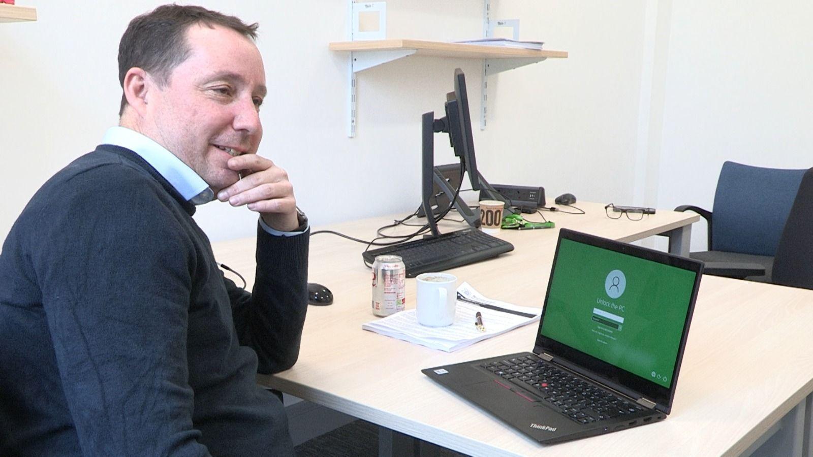 Councillor Richard Jackson, sitting at an office desk with a laptop open in front of him, looking off to the side of the room