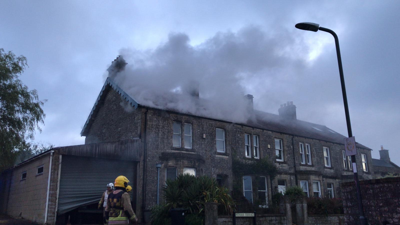 A house with smoke on the roof in Timsbury with firefighters visible