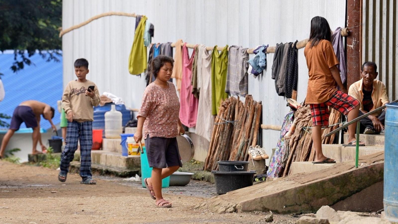 People carrying on with their daily lives outside a displacement camp in Manipur