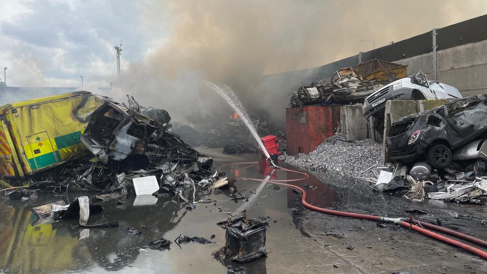 An old ambulance and cars are hosed down after being burnt in the fire