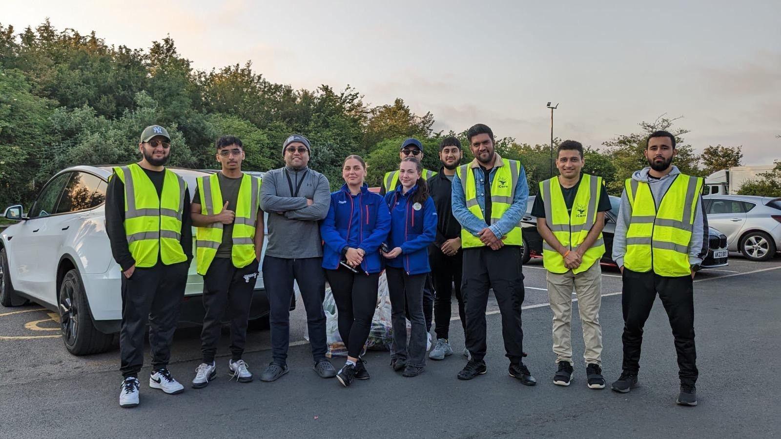 People standing in a row- wearing high-visibility green jackets- and Akeel (3rd from left) wearing a grey jumper and blue jeans