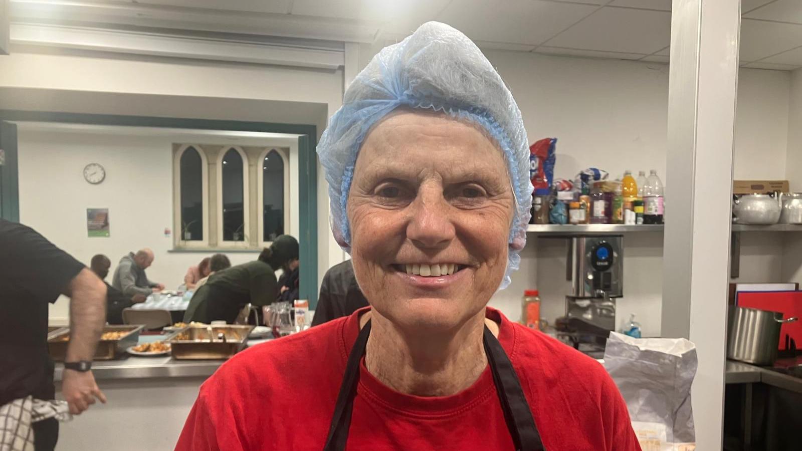 Carol Snowball, wears a hairnet in a kitchen. 