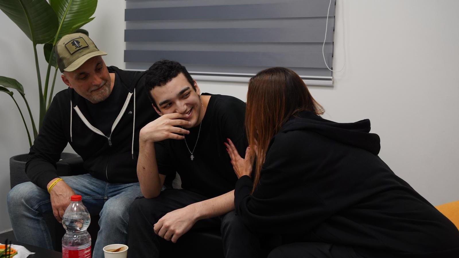 Mr Alexander sits with two family members and smiles.