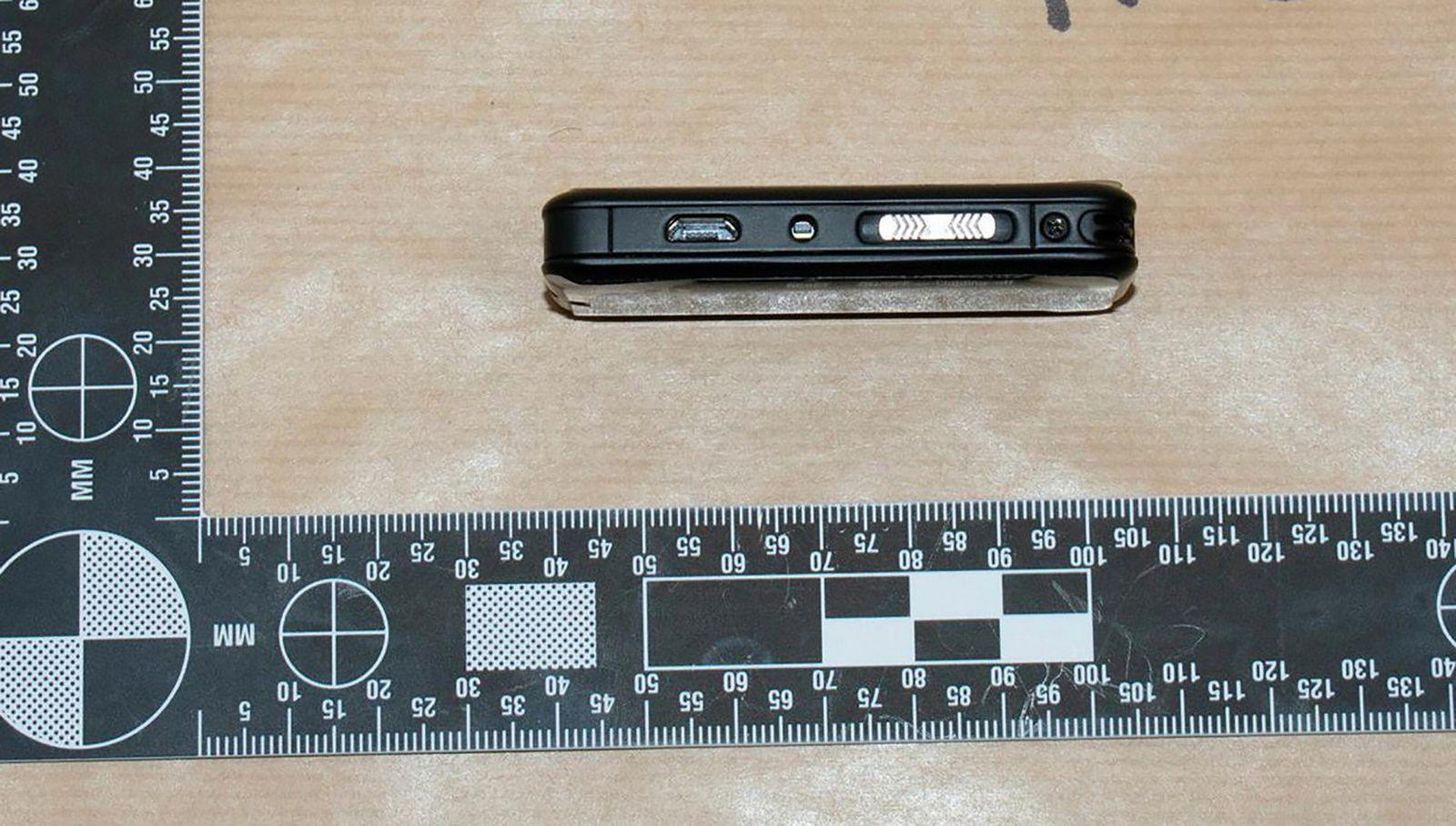 A thumb-sized spy camera with a black and white ruler for scale