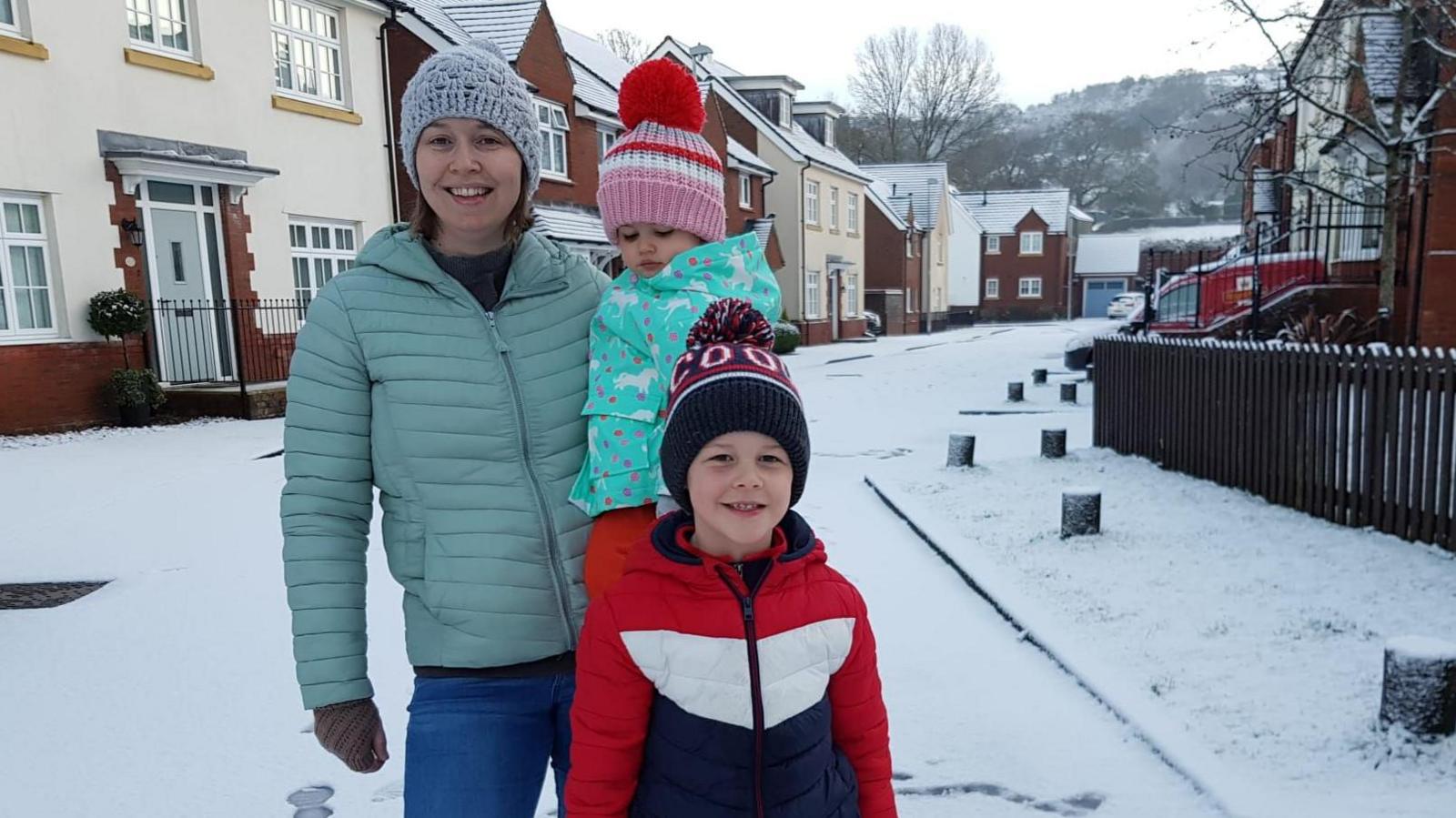 Nicola, Oscar and Ffion in the snow. All are wearing padded warm coats and bobble hats. 