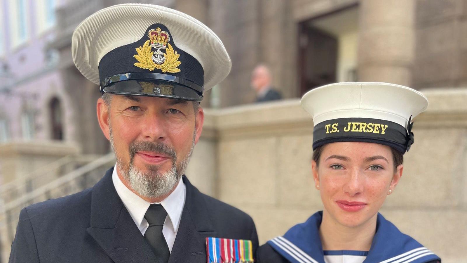 David smiles at the camera as he stands next to Evie and they are both in uniform