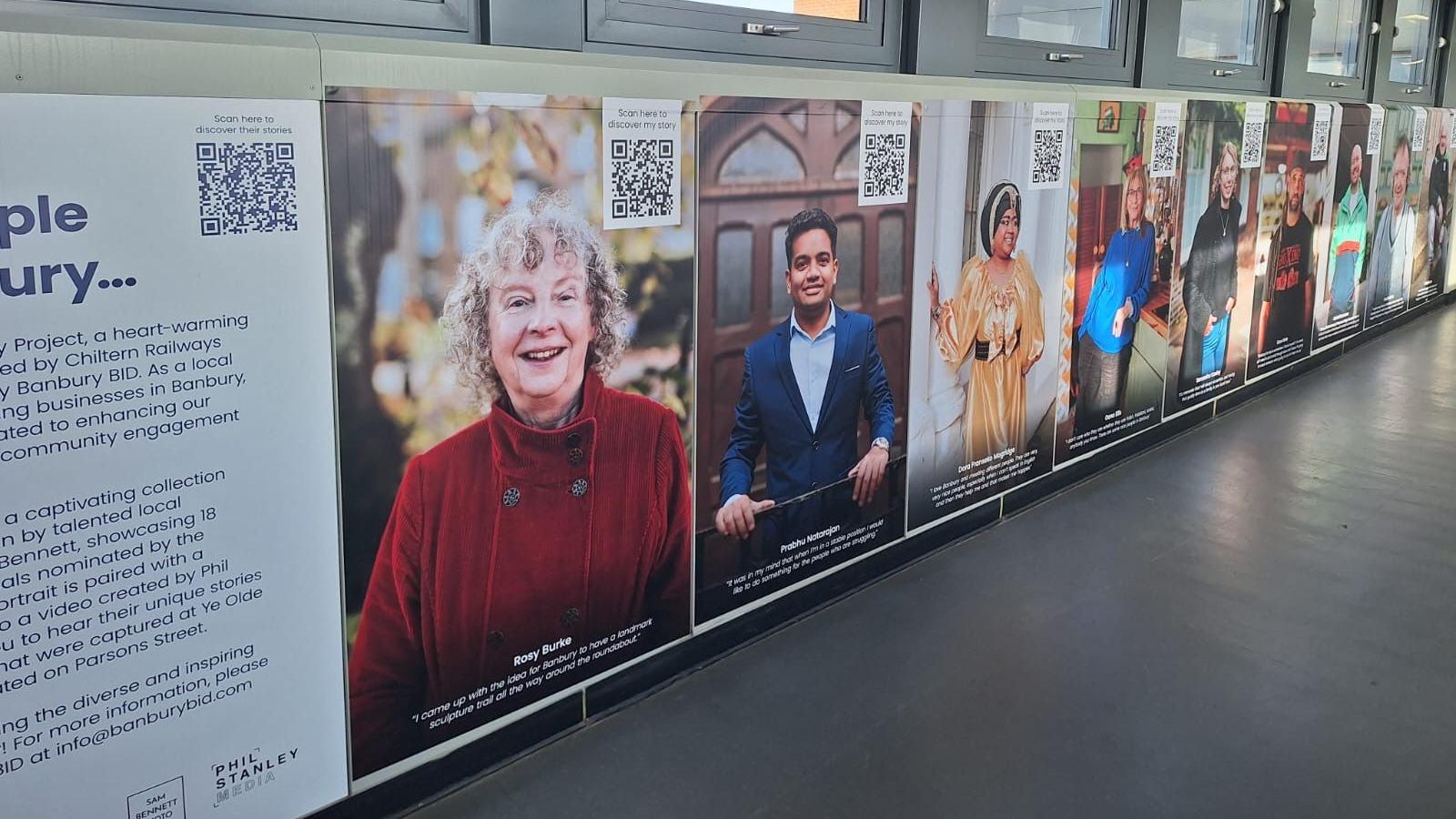 Some of the portraits lining the wall at Banbury Station with the QR codes on them.