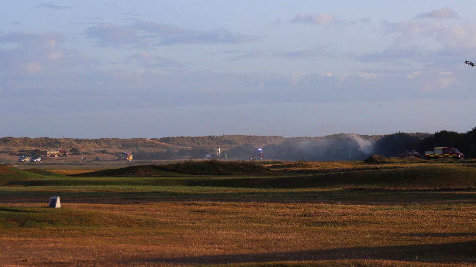 A landscape shot of the golf course, smoke can be seen.