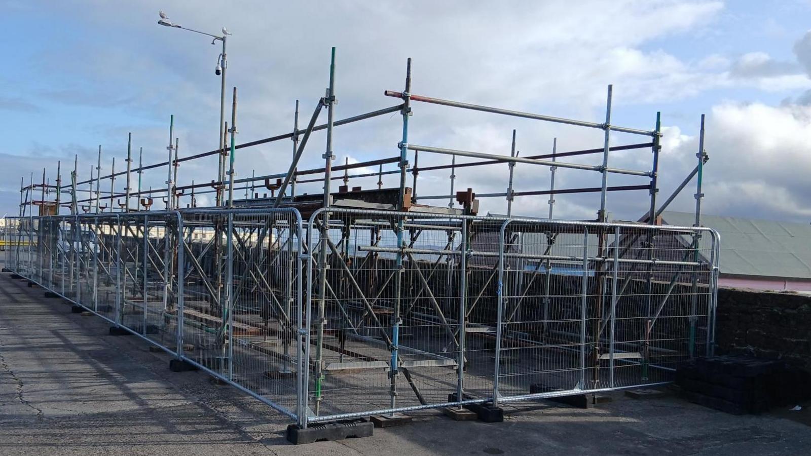 Scaffolding with metal fencing place around it on the harbourside in Peel.