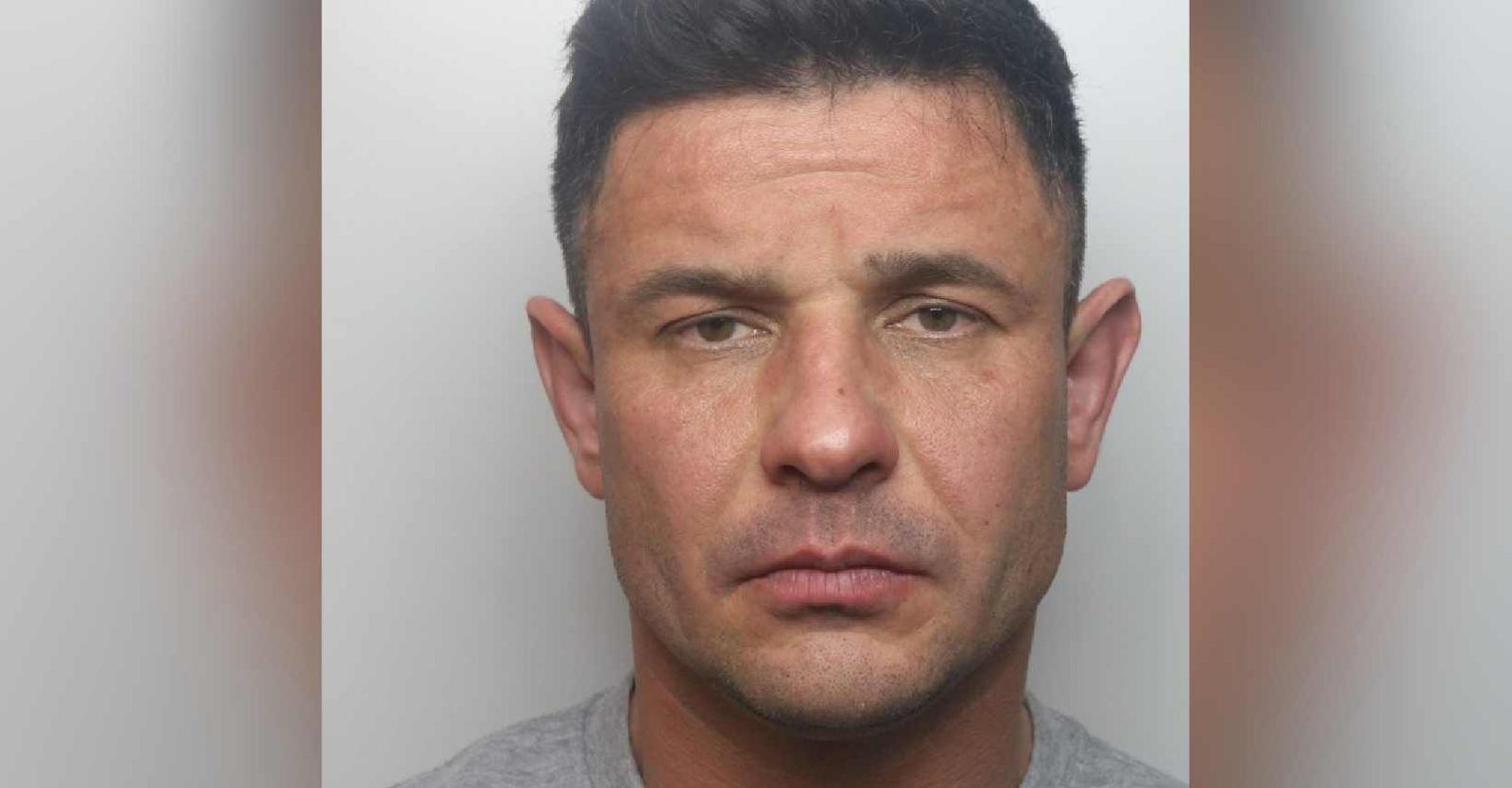 Police mugshot of Jakub Nowicki looking at the camera. He has dark hair and wears a police issue grey t-shirt.