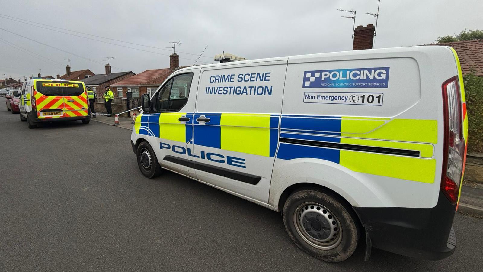 Crime scene investigation van, police van and cordon on a street of bungalows