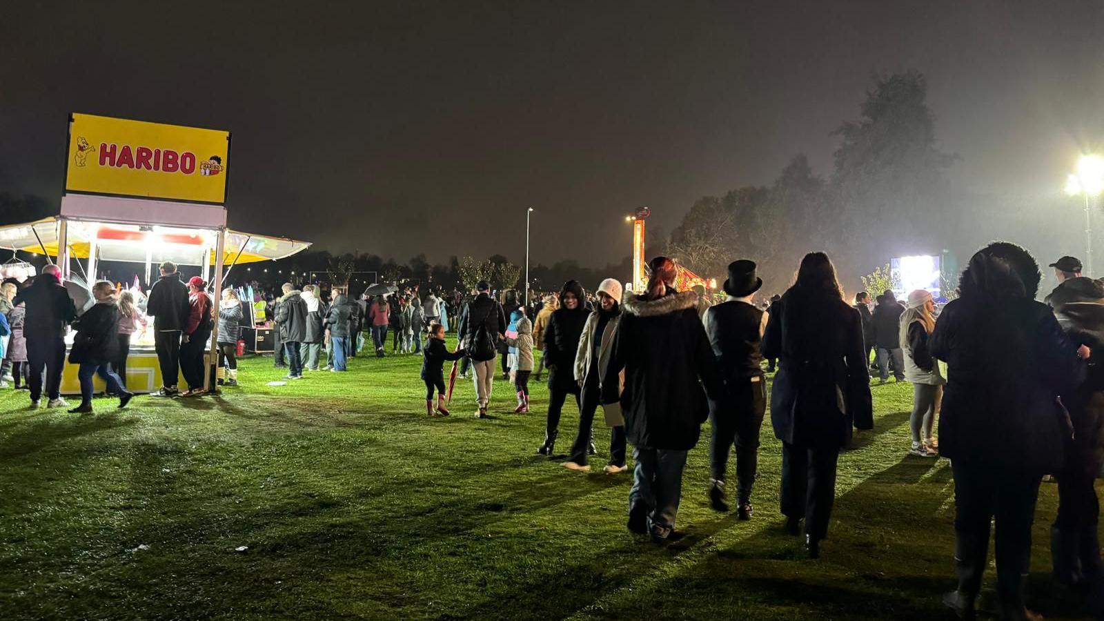 A crowd of people at the Racecourse in Northampton. A food stall is visible to the left.