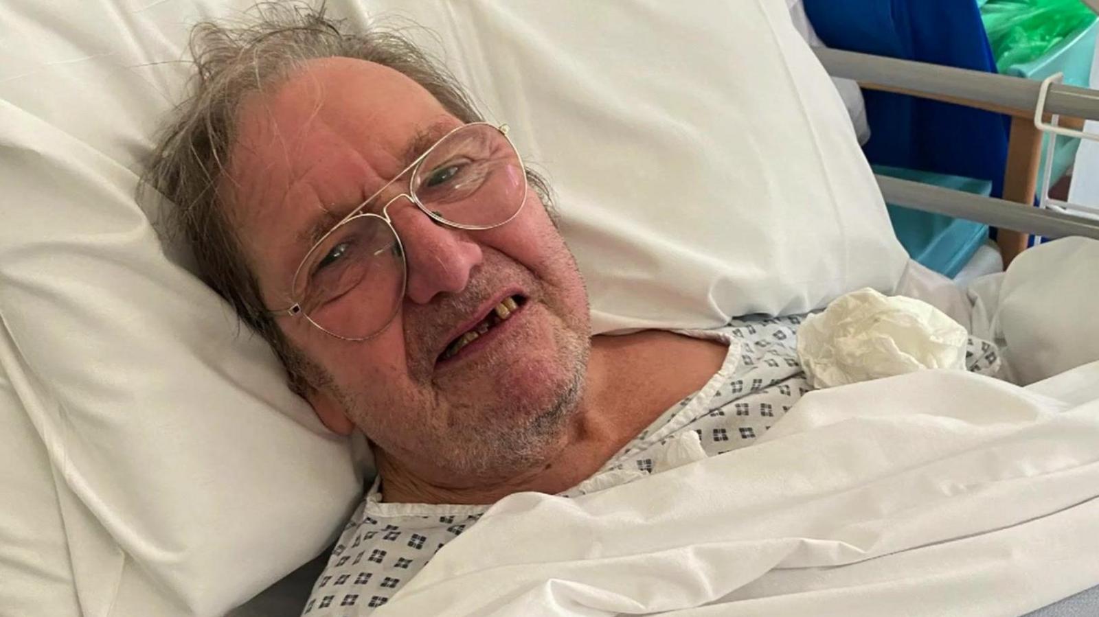 Mr Sexton, a man wearing glasses laying in a hospital bed.