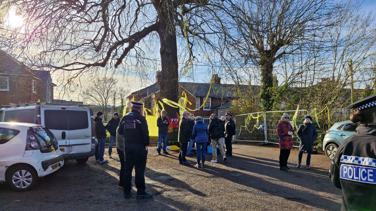 Police officers engaging with campaigners at the oak tree, which is situated in a car park and covered in yellow ribbons.