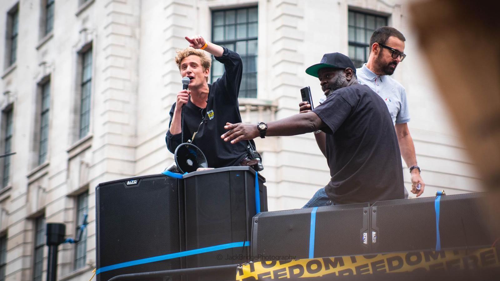 George Fleming speaking into a microphone standing on a sound system outside