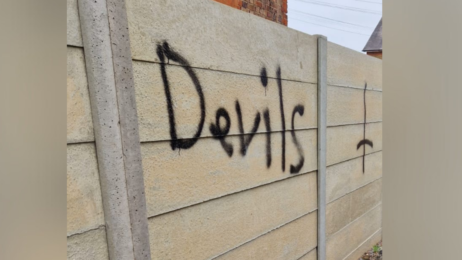 A wooden fence graffitied with the word "devil".