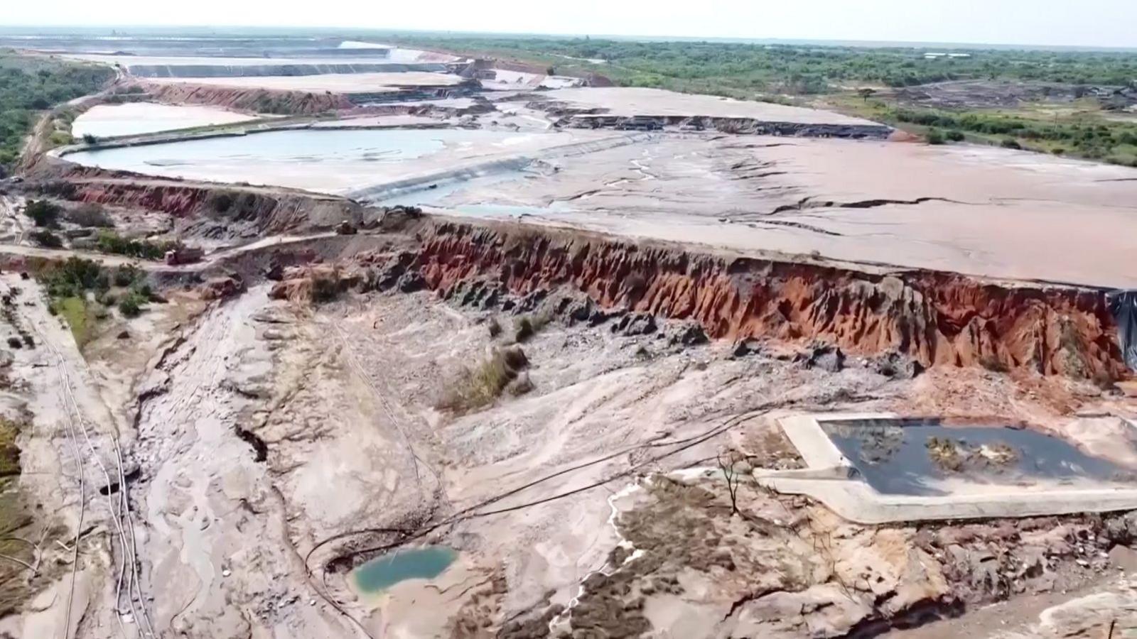 Aerial showing path of tailings dam having breached into the environment. Mud residue has covered a vast area in the foreground of the image.