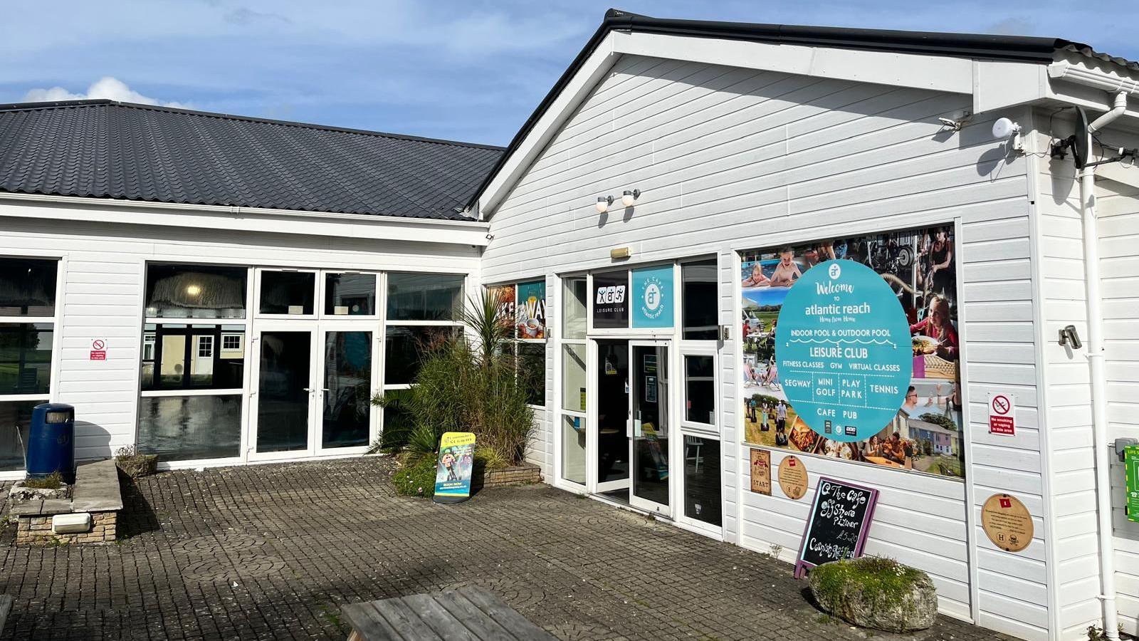 Atlantic Reach Holiday Park - a building with white wooden cladding, with the swimming barely visible through glass double doors in front