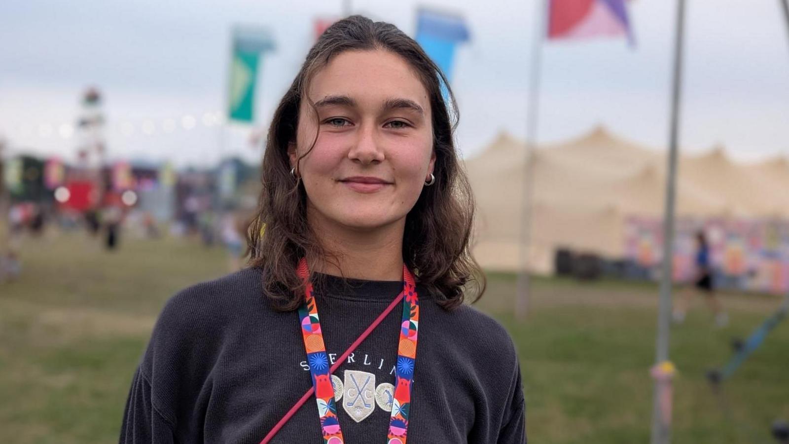 Jasmine Dunston wearing a dark sweatshirt, standing in a festival field with flags behind.