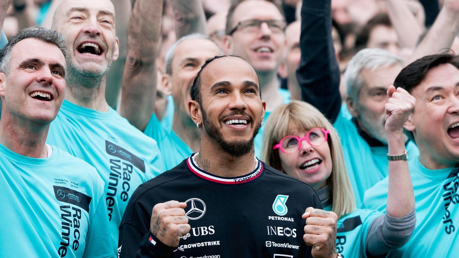 Lewis Hamilton dressed in a black Mercedes shirt alongside staff in turquoise shirts.