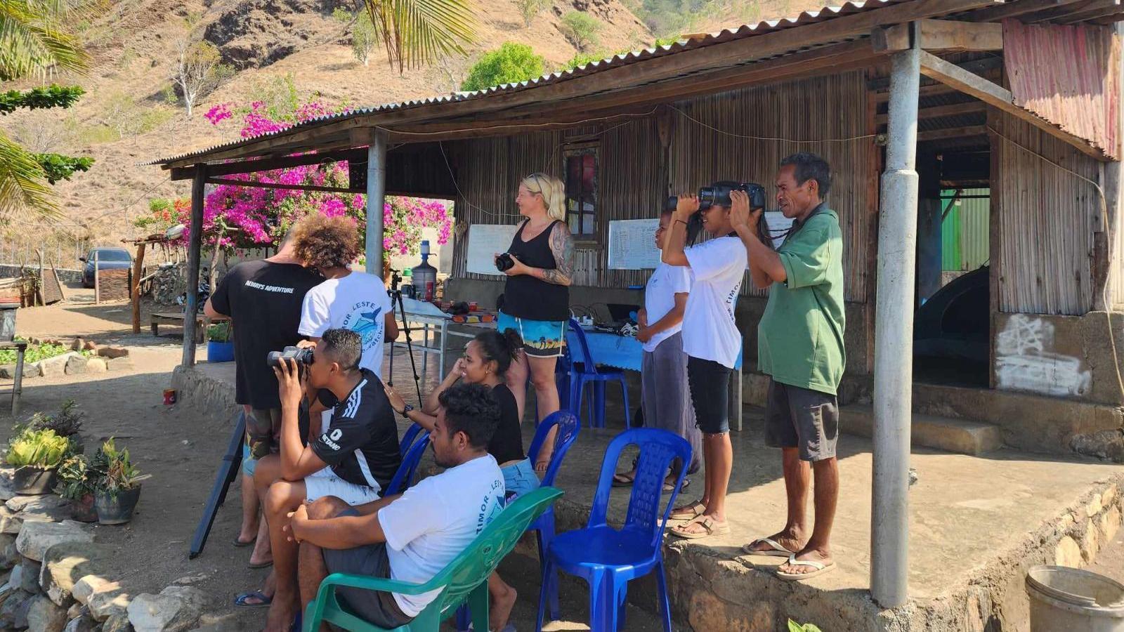 Volunteers attempt to spot cetaceans through their binoculars their cameras at a research station outside the da Cunha's village home in Subaun 