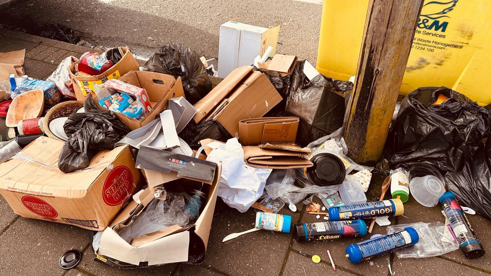 A pile of rubbish is dumped on street, from cardboard boxes to black rubbish bags filled with items