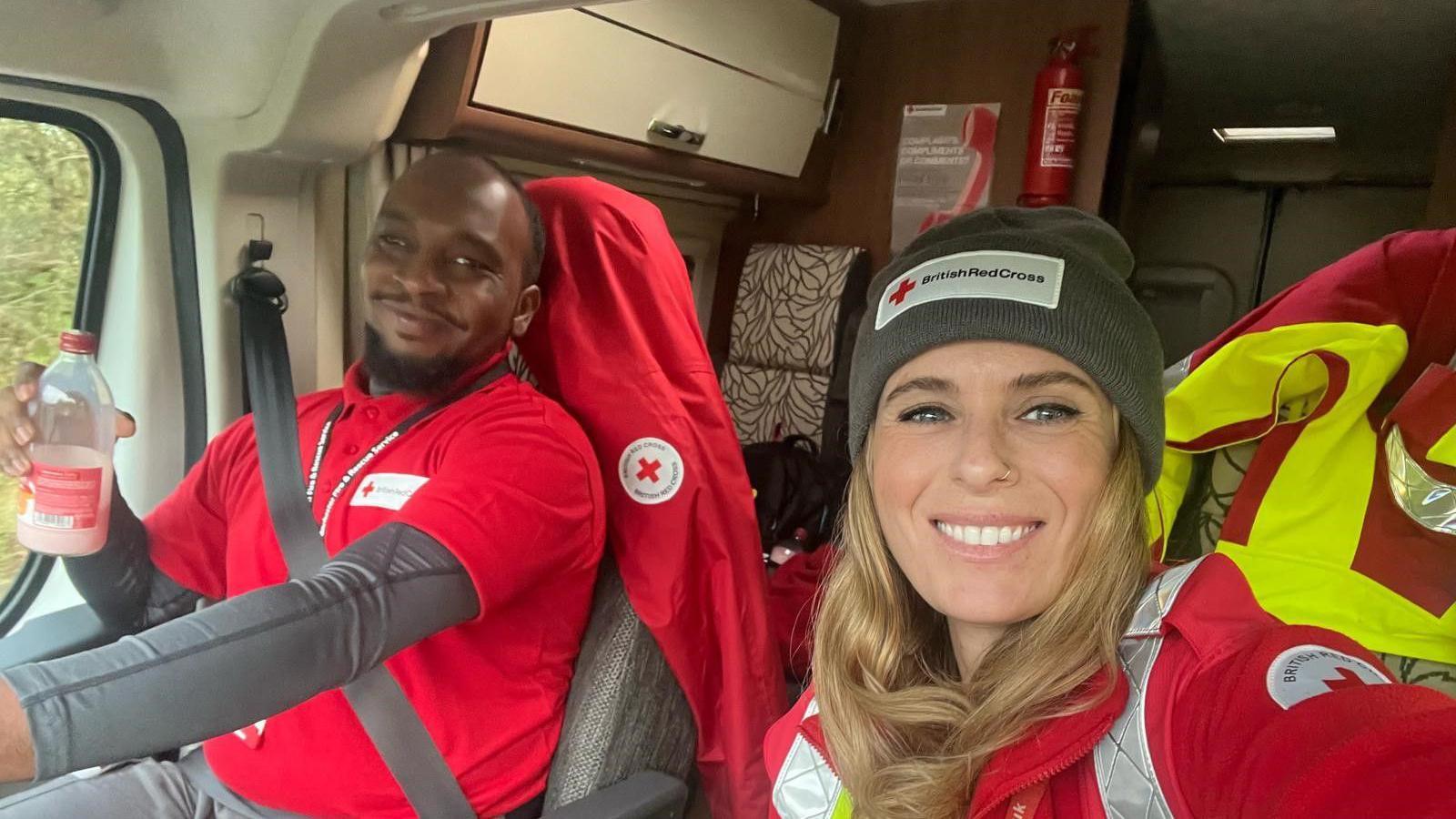 Mohammed Abdul Karim in his Red Cross uniform in the seat of an ambulance. A female colleague is sat next to him and is taking a selfie of them both.