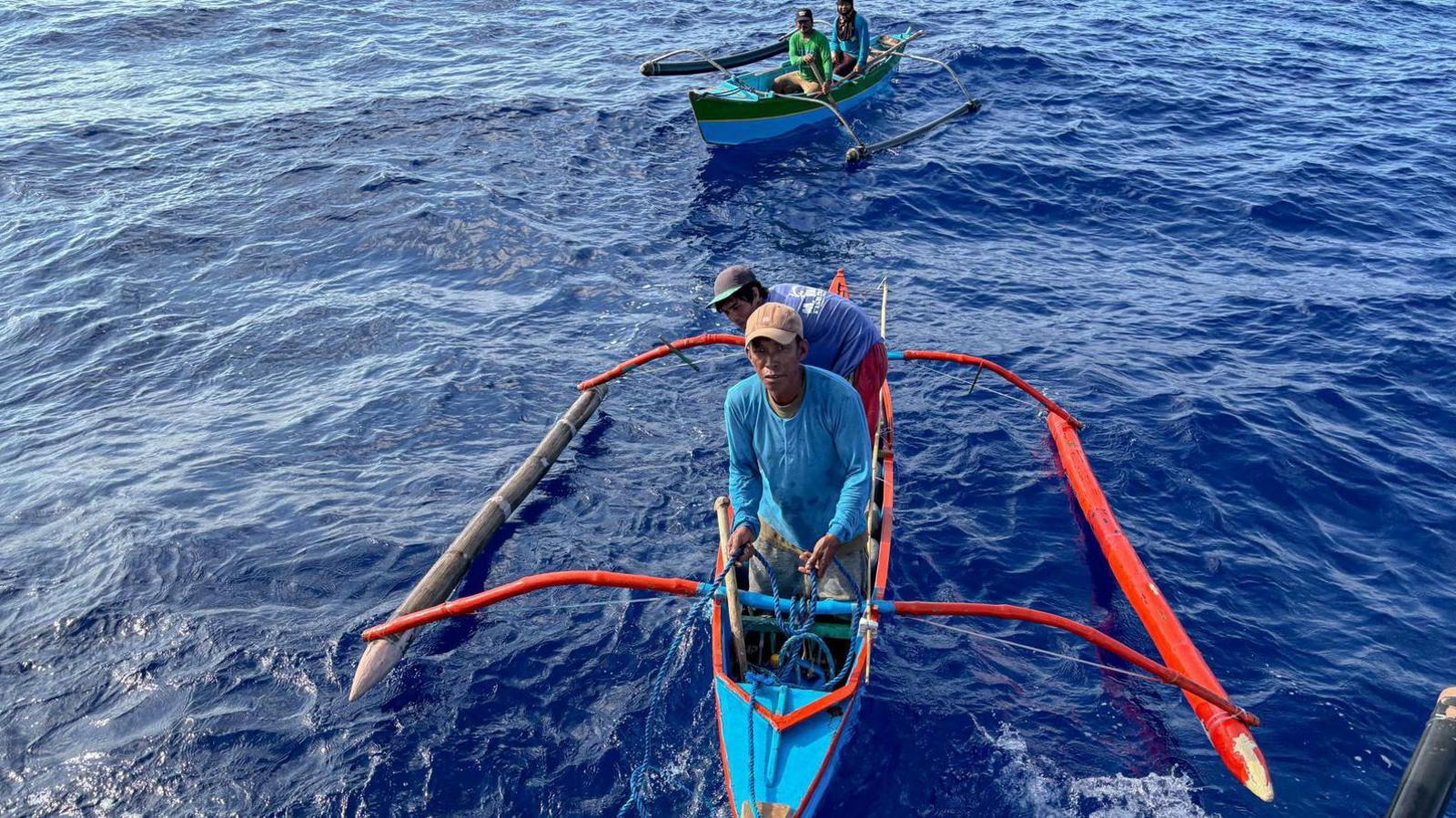 Fishermen gathered round the Philippine coast guard boat to receive aid