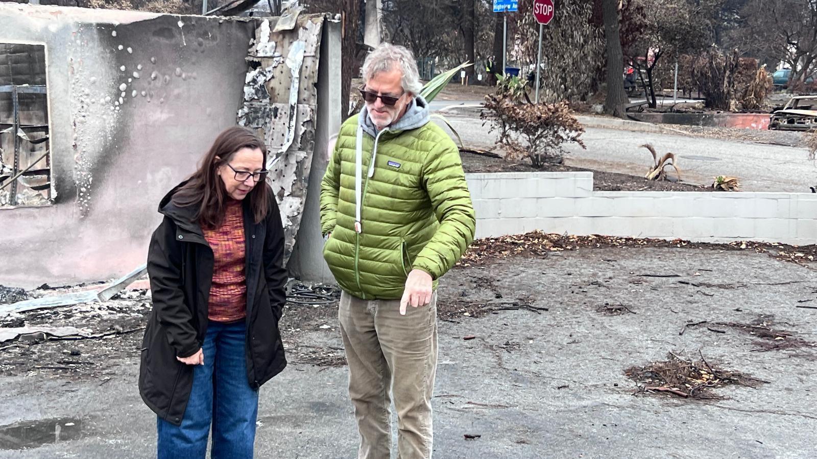 Wearing winter coats, Mark Worthington and his partner Mindy Elliot inspect their fire-destroyed property in Altadena